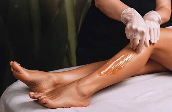 application d'une cire pour épilation d'une demi-jambe